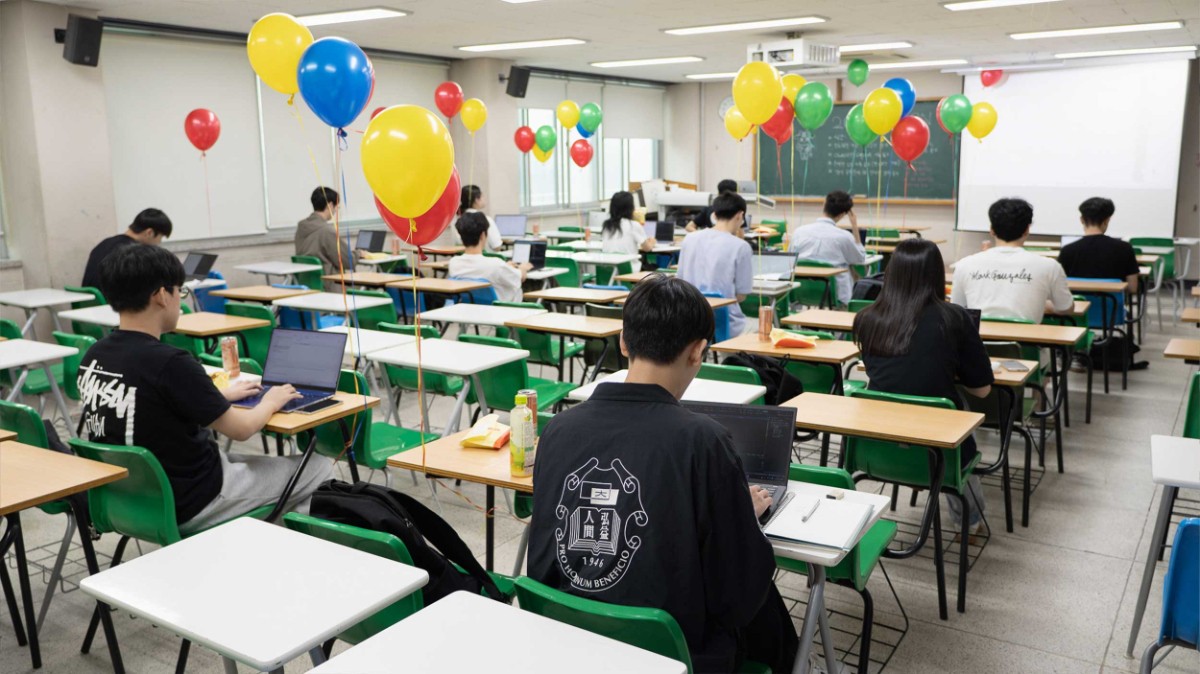 칠판과 스크린을 향해 줄지어 앉은 참가자들. 책상 사이마다 풍선이 떠 있다.